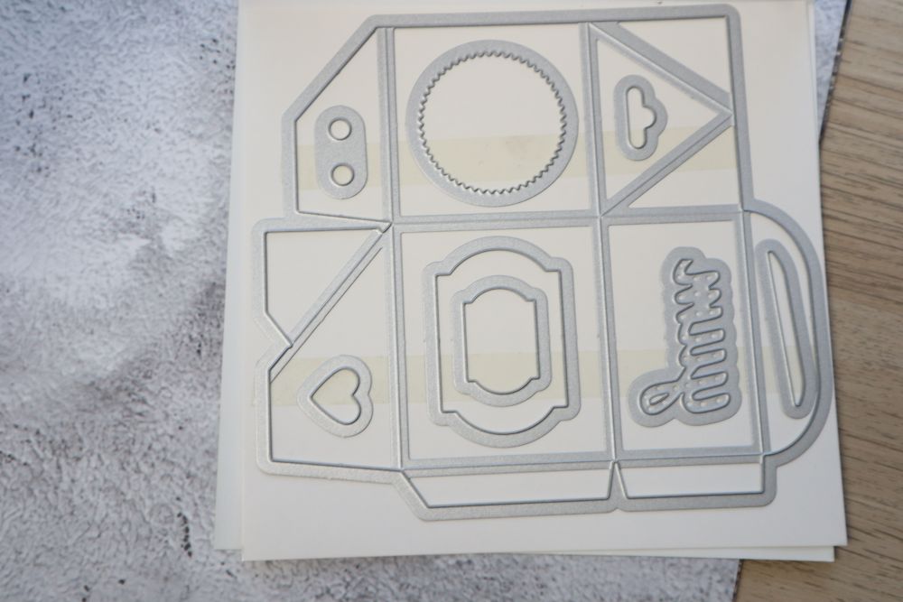 Baker’s Box Thinlits Dies arranged on storage sheet with box and decorative elements